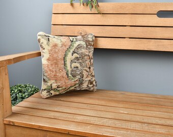 Könnte beinhalten: Eine braune Holzbank mit einem gemusterten Kissen. Das Kissen hat ein florales Design in Braun-, Grün- und Cremetönen.