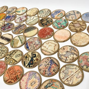 May include: A set of 30 round coasters featuring a variety of colourful and patterned fabric designs. The coasters are made of fabric with a brown woven border.