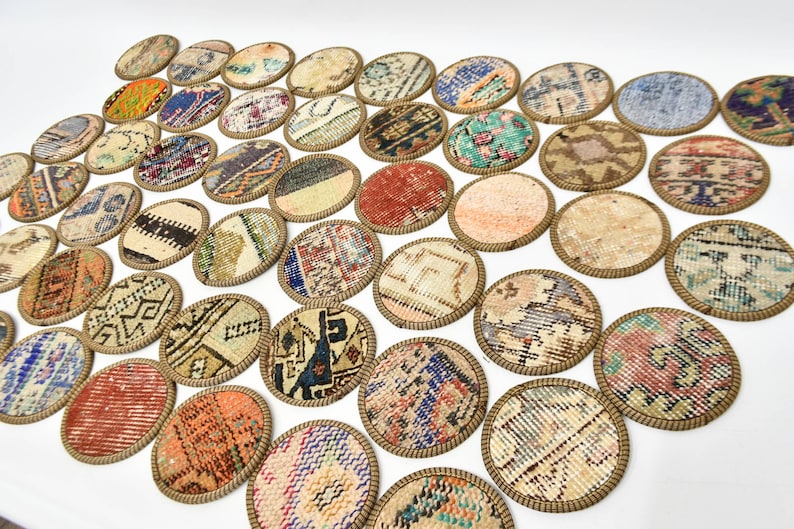 May include: A set of 30 round coasters featuring a variety of colourful and patterned fabric designs. The coasters are made of fabric with a brown woven border.