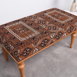 May include: A brown wooden bench with a patterned cushion. The cushion has a geometric design with brown, black, and white colors.