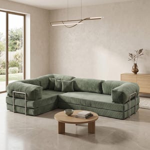 Puede incluir: Sal&oacute;n moderno con un gran sof&aacute; esquinero verde salvia con soportes de brazo met&aacute;licos. Una mesa de centro redonda de madera contiene libros y un cuenco. Una l&aacute;mpara minimalista cuelga encima y un mueble de madera est&aacute; en el fondo.