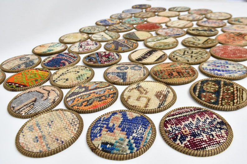 May include: A set of round coasters featuring colourful, intricate patterns woven into the fabric. The coasters are edged with a gold-coloured trim.