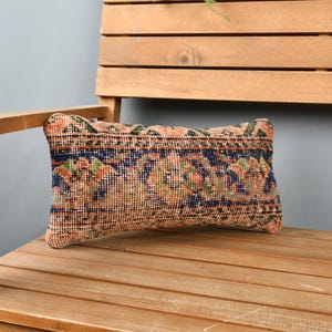 May include: A rectangular throw pillow with a colorful floral pattern in shades of orange, blue, and green. The pillow is made of a woven fabric and has a fringed edge.