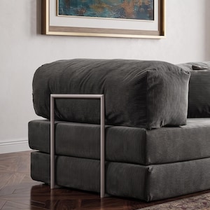 May include: A modern, modular sofa in a dark gray corduroy fabric. The sofa features a stacked design with a rectangular shape and a metal frame. The cushions are plush and the overall aesthetic is contemporary and minimalist.