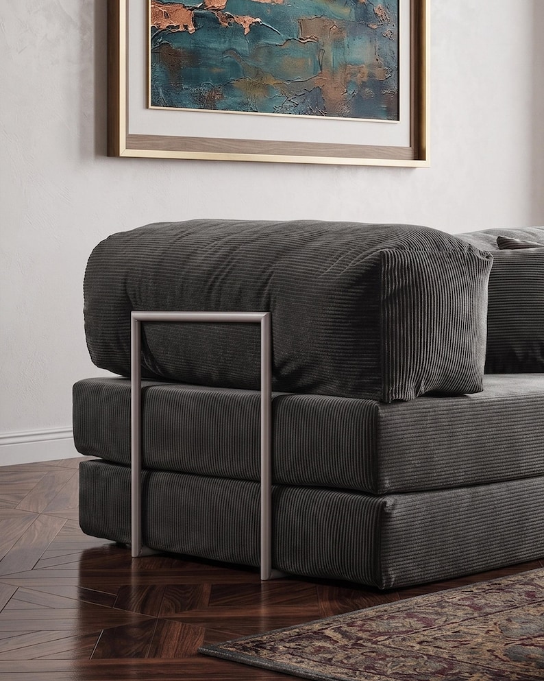 May include: A modern, modular sofa in a dark gray corduroy fabric. The sofa features a stacked design with a rectangular shape and a metal frame. The cushions are plush and the overall aesthetic is contemporary and minimalist.