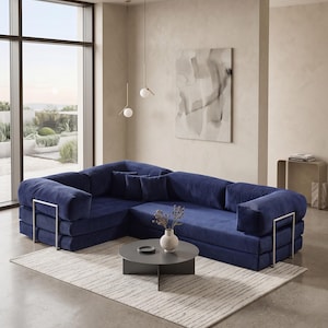 Puede incluir: Un moderno sof&aacute; seccional azul marino con detalles met&aacute;licos plateados. El sof&aacute; est&aacute; sobre una alfombra clara, con una mesa de centro gris oscuro y un jarr&oacute;n con flores secas. La habitaci&oacute;n tiene grandes ventanales y paredes de tonos neutros.