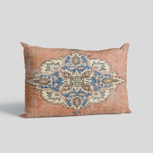May include: A rectangular throw pillow with a vintage-style patterned design in shades of orange, blue, and white. The pattern features a central medallion with intricate floral motifs.