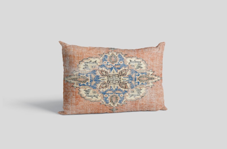 May include: A rectangular throw pillow with a vintage-style patterned design in shades of orange, blue, and white. The pattern features a central medallion with intricate floral motifs.