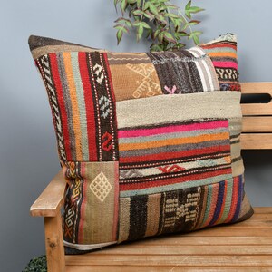 Peut inclure: Un coussin carré en patchwork avec une variété de couleurs et de motifs. Le coussin présente des rayures, des formes géométriques et un mélange de textures. Il repose sur un banc en bois, mettant en valeur son attrait décoratif.