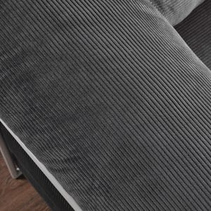 May include: Close-up of a section of a dark gray corduroy sofa. The fabric has a ribbed texture, with the ridges running diagonally across the frame. The sofa appears to be part of a larger set, with a white trim and metal frame visible.
