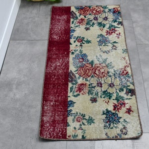 May include: A vintage floral runner rug with a red and white distressed border. The rug features a cream background with a floral pattern in shades of pink, blue, and green.