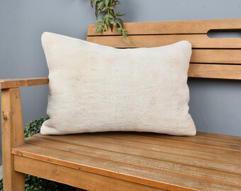 May include: A white linen pillow sits on a wooden bench with a natural wood finish. The bench has a slatted design and a cutout handle on the back.