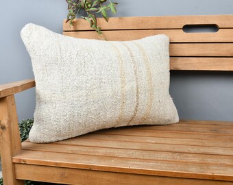 May include: A white throw pillow with a subtle beige stripe pattern, resting on a wooden bench.