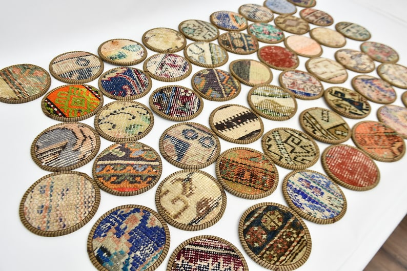 May include: A set of round coasters featuring colourful patterned fabric with a gold trim. The coasters are arranged in rows on a white surface.