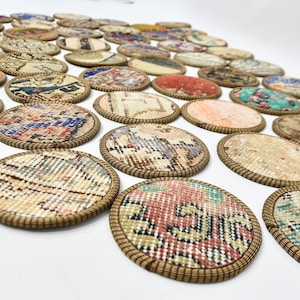 May include: A set of round, colourful coasters made from repurposed rug fabric. Each coaster has a brown woven trim and features a unique pattern.