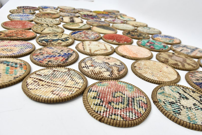 May include: A set of round, colourful coasters made from repurposed rug fabric. Each coaster has a brown woven trim and features a unique pattern.
