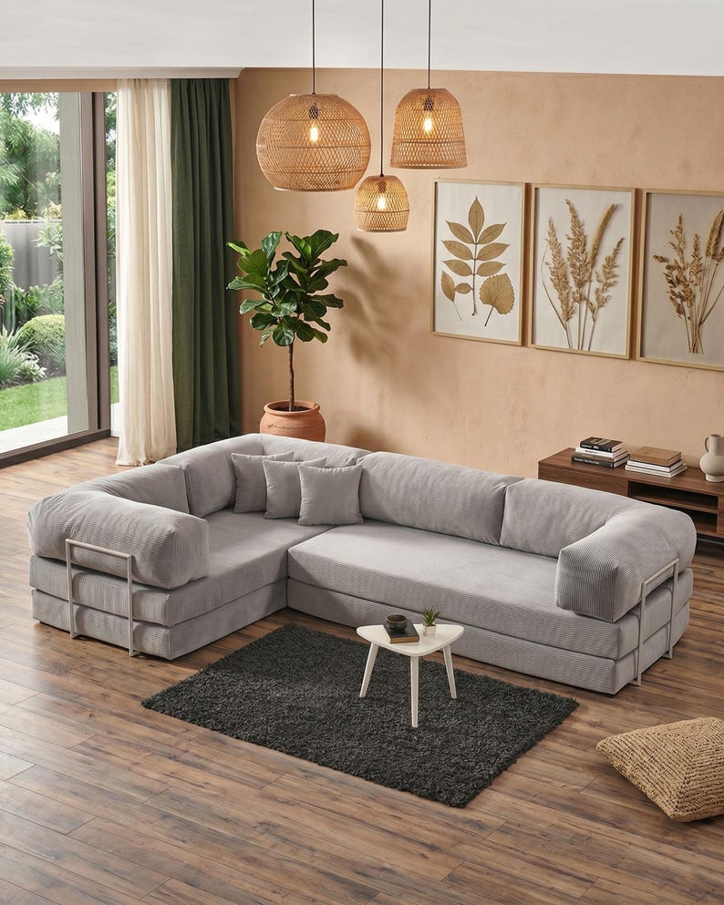 Puede incluir: Un gran sof&aacute; seccional gris claro con un dise&ntilde;o moderno. El sof&aacute; tiene un perfil bajo, con brazos cuadrados y detalles met&aacute;licos. Una peque&ntilde;a mesa blanca y una alfombra gris oscura est&aacute;n delante. L&aacute;mparas colgantes tejidas cuelgan.