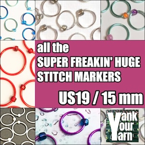 May include: A collection of large, colorful stitch markers in various colors, including red, blue, white, purple, and silver. The markers are 15 mm in diameter and are labeled "US19 / 15 mm".