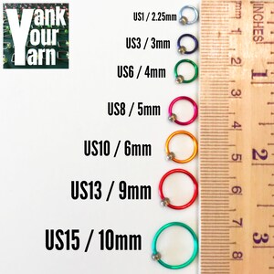 K&ouml;nnte beinhalten: Ein Lineal mit verschiedenen farbigen Stricknadeln, die mit US-Gr&ouml;&szlig;en und entsprechenden Ma&szlig;en in Millimetern beschriftet sind. Die Gr&ouml;&szlig;en sind US1/2,25 mm, US3/3 mm, US6/4 mm, US8/5 mm, US10/6 mm, US13/9 mm und US15/10 mm.