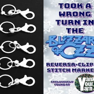 May include: Five white plastic stitch markers with a ring and a clip. The markers are arranged vertically in a row. The text on the image reads "Took a wrong turn in the Blizzard of Oz. Reversa-clippy stitch markers. Exclusively found at Yank Our Yarn."