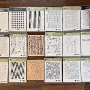 May include: A collection of clear plastic stamp sets with various designs. The sets include patterns like buffalo check, vertical lines, dots, and text. Other sets feature floral, abstract, and map designs. The text on the sets includes "ALL WIRED UP" and "BUFFALO CHECK".
