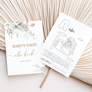 May include: A printable baby's first alphabet book with a green and gold watercolor design. The cover says "Baby's First abc book - made with love". The first page of the book is a coloring page with the letter A and the word "Airplane" with a picture of an airplane.