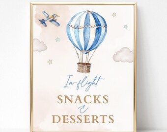 May include: A printable sign with a blue and white striped hot air balloon, a small airplane, and clouds. The text on the sign reads "In-flight Snacks & Desserts".