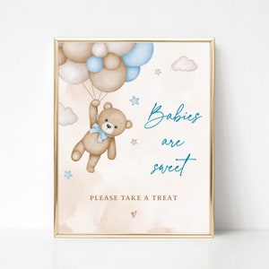 Puede incluir: Impresi&oacute;n enmarcada con borde dorado. Ilustraci&oacute;n en acuarela de un oso de peluche sosteniendo globos. El oso lleva un lazo azul. El texto dice: "Babies are sweet" y "Please take a treat".