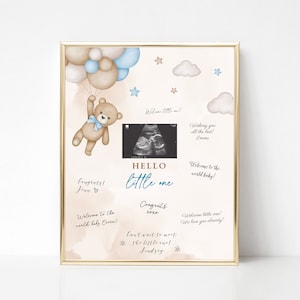 Puede incluir: Un cartel de baby shower imprimible con un osito de peluche sosteniendo globos, una imagen de ultrasonido y el texto "HELLO little one". El cartel también incluye el texto "¡Bienvenido al mundo bebé!" y "¡Felicidades!" con nombres y mensajes.