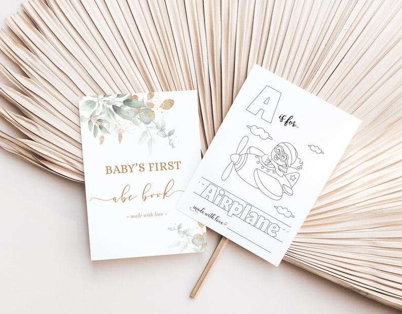 May include: A printable baby's first alphabet book with a green and gold watercolor design. The cover says "Baby's First abc book - made with love". The first page of the book is a coloring page with the letter A and the word "Airplane" with a picture of an airplane.