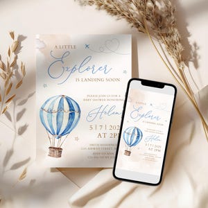 May include: Baby shower invitation featuring a watercolor hot air balloon in blue and white. The invitation reads "A Little Explorer is Landing Soon" with event details. A smartphone displays the same design.