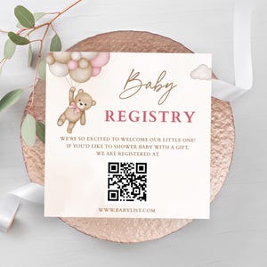 Peut inclure: Annonce de liste de naissance avec un ours en peluche tenant des ballons. La carte affiche les mots "Baby Registry" en écriture cursive, un code QR et une adresse de site web. Le fond est de couleur rose pâle.