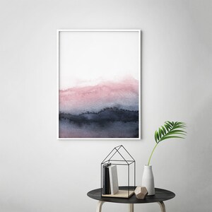 May include: Abstract watercolour painting in shades of pink and blue, framed in a white frame. The painting depicts a landscape with a hazy, atmospheric effect.
