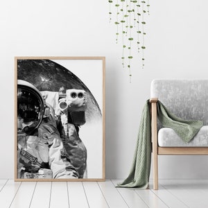 May include: A black and white photograph of an astronaut in a spacesuit standing in front of the moon. The astronaut's helmet reflects the moon's surface.