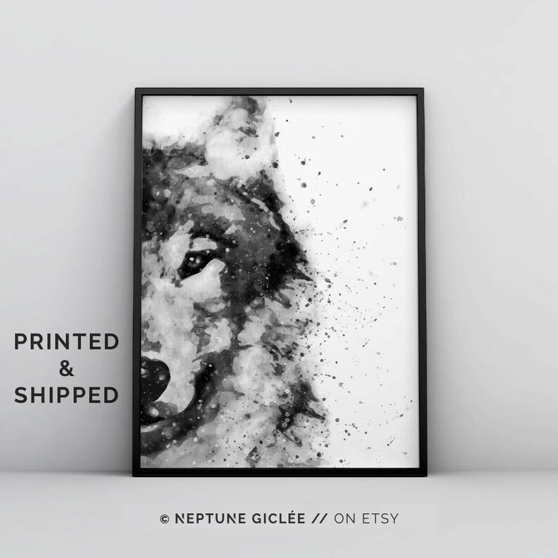 Op de afbeelding: Zwart-witte aquarelverf van een wolvenkop. Het gezicht van de wolf is gedeeltelijk bedekt met een spatten witte verf. Het schilderij is ingelijst in een zwart frame.