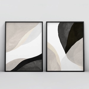 May include: Two black framed abstract art prints with white, gray, and black watercolor-like shapes. The prints have a modern minimalist style.
