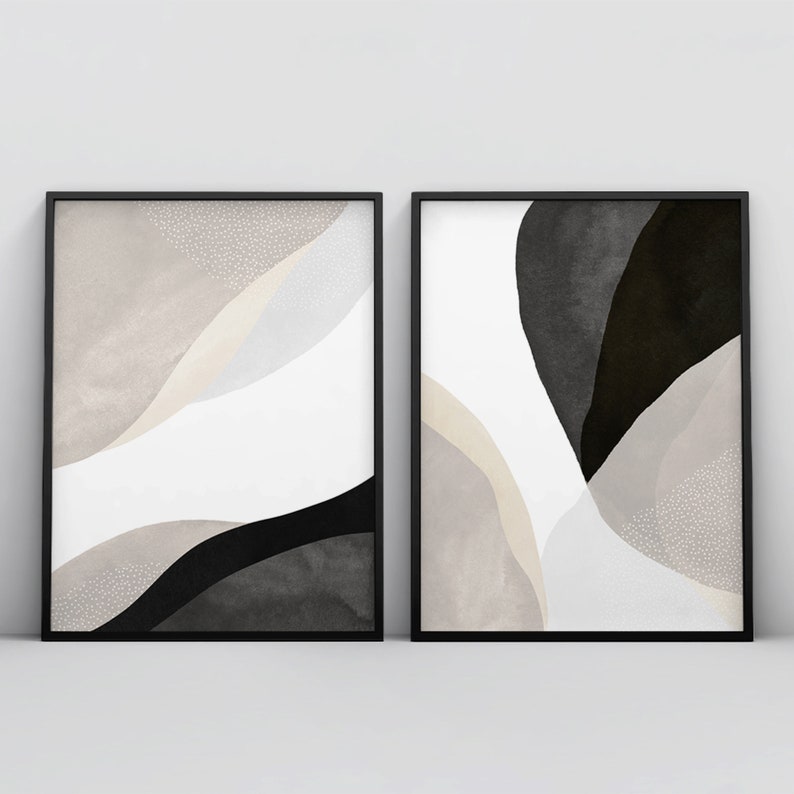 May include: Two black framed abstract art prints with white, gray, and black watercolor-like shapes. The prints have a modern minimalist style.