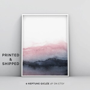 May include: Abstract watercolour painting in shades of pink and blue. The painting features a gradient of colour, starting with a light pink at the top and transitioning to a dark blue at the bottom. The painting is framed in a white frame.