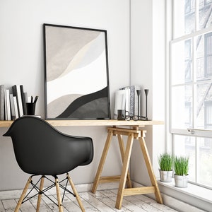 May include: A black and white abstract art print in a black frame hangs above a wooden desk with a black chair. The desk is supported by two wooden sawhorses. There are two potted plants on the floor next to the desk.