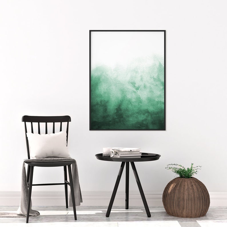Puede incluir: Una silla negra con un coj&iacute;n blanco se encuentra junto a una mesa auxiliar negra con una pila de libros encima. Una pintura de acuarela verde cuelga de la pared detr&aacute;s de la silla. Una cesta de mimbre con una planta verde se encuentra en el suelo junto a la mesa.