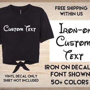 May include: Black t-shirt with a white iron-on decal that says "Custom Text" in a Disney-inspired font. The shirt is tied at the bottom.  "Iron-on decal in font shown. 50+ colors. Vinyl decal only. Shirt not included." is written below the image.