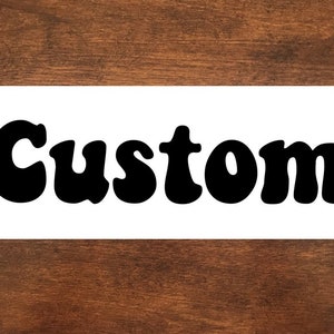 May include: A white sign with the word "Custom" written in black, bold, retro-style lettering.