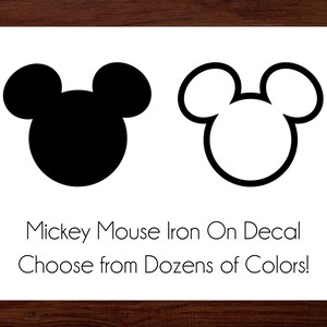 May include: Two Mickey Mouse head iron-on decals, one solid black and one outlined in black. Text below reads "Mickey Mouse Iron On Decal Choose from Dozens of Colors!"