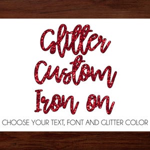 May include: White card with red glitter text that reads "Glitter Custom Iron On". Below the text is the phrase "CHOOSE YOUR TEXT, FONT AND GLITTER COLOR". The card is set against a dark wood background.