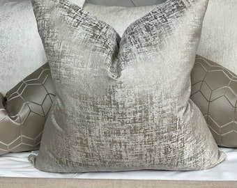May include: A silver and white decorative throw pillow with a textured, distressed pattern. The pillow is made of a soft, luxurious fabric.