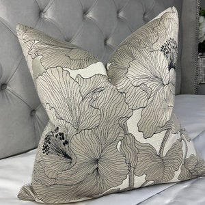 May include: A decorative throw pillow with a floral pattern in shades of beige and black. The pillow features a large, stylized flower design with intricate details.