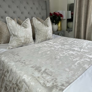 May include: A grey and white patterned bedspread with two matching grey and white patterned throw pillows on a grey tufted headboard.