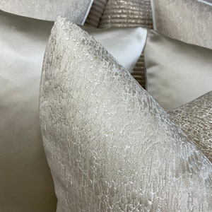 May include: Close-up of a white pillow with a textured surface. The pillow is made of a soft, luxurious fabric.