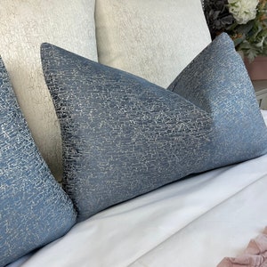 May include: Three decorative throw pillows with a textured, crackled fabric. The pillows are in shades of blue and white.