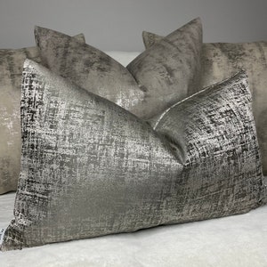 Peut inclure: Un ensemble de quatre coussins décoratifs avec un motif abstrait argenté et gris. Les coussins sont faits d'un tissu doux et luxueux et ajouteraient une touche d'élégance à n'importe quelle pièce.
